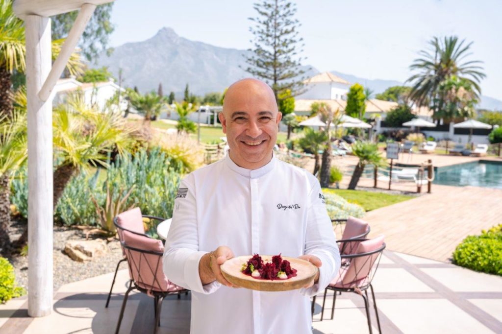 Diego del Río, Executive Chef of the Boho Club stands in front of La Concha Mountain in marbella holding one of his dishes