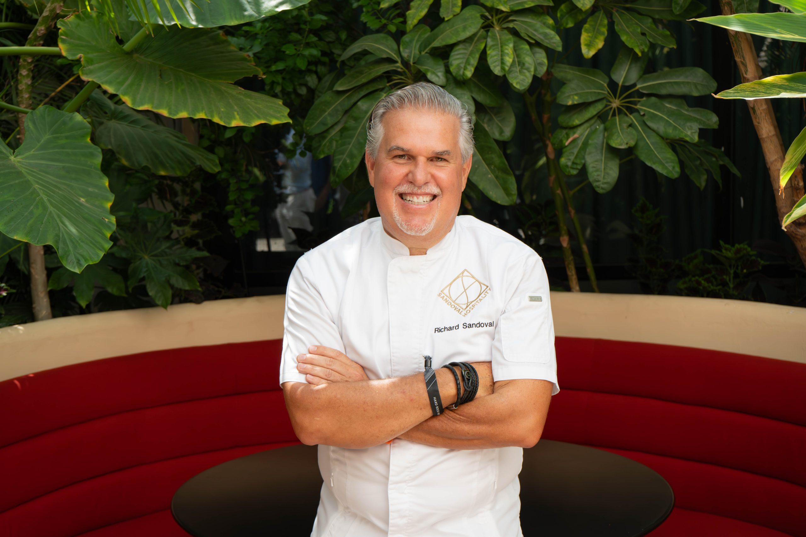 Richard Sandoval standing in the garden terrace of his new Zengo Marbella Restaurant on Spain's costa del sol. He is wearing his chef's jacket and behind him are sub tropical plants