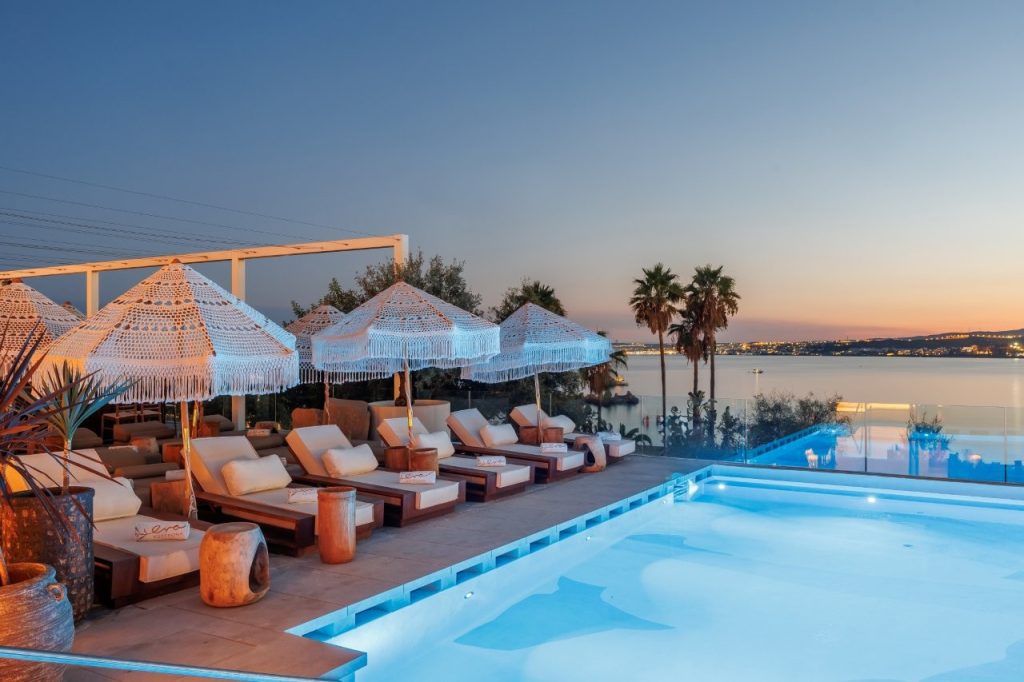 View of Pool, edged by sunbeds and parasols as the sun sets
