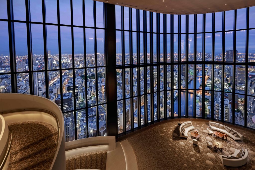 Interior of the 40th floor lobby of the Conrad Osaka shwoing 4 storeys of floor to ceiling glass creating a hige space with panoramic views fo osaka