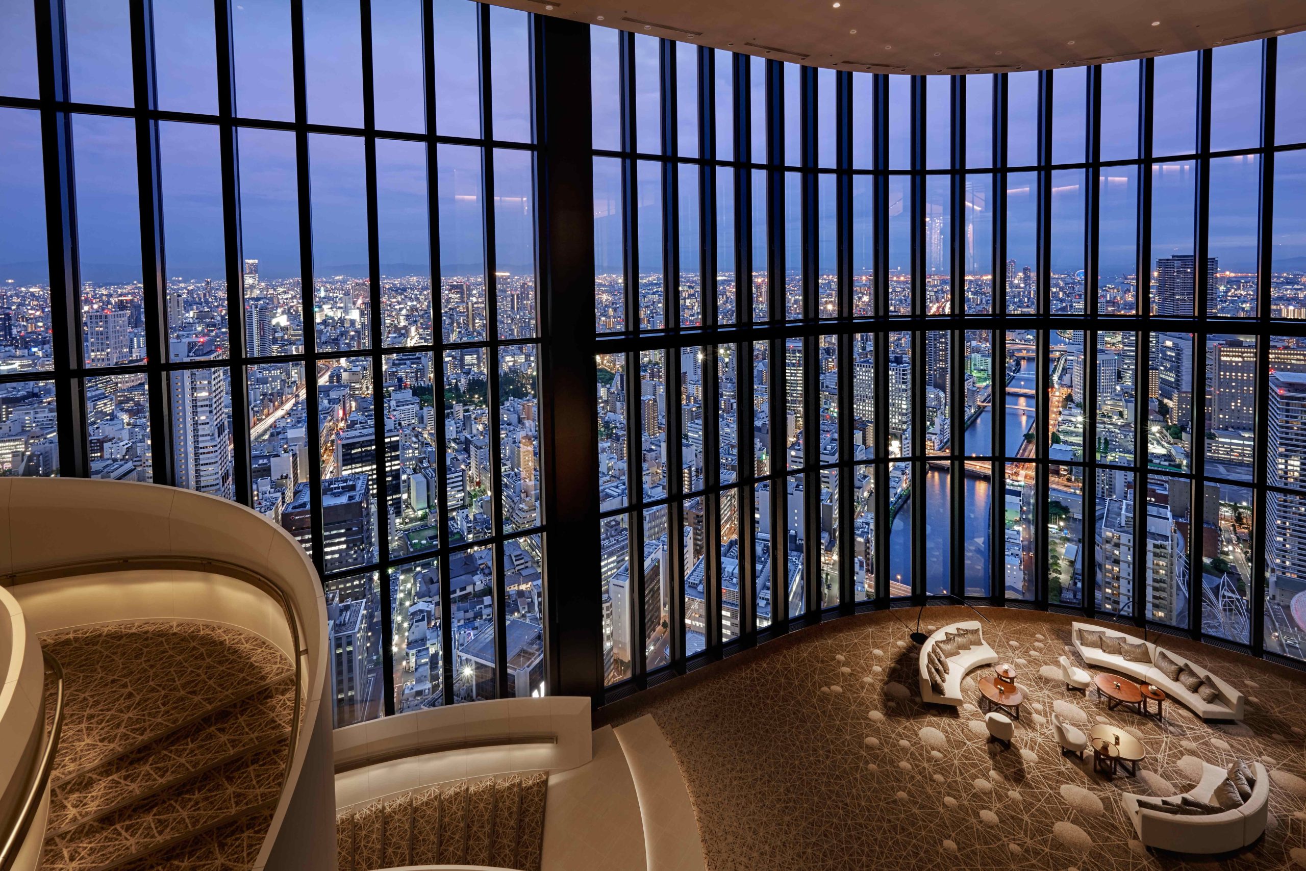 Interior of the 40th floor lobby of the Conrad Osaka shwoing 4 storeys of floor to ceiling glass creating a hige space with panoramic views fo osaka